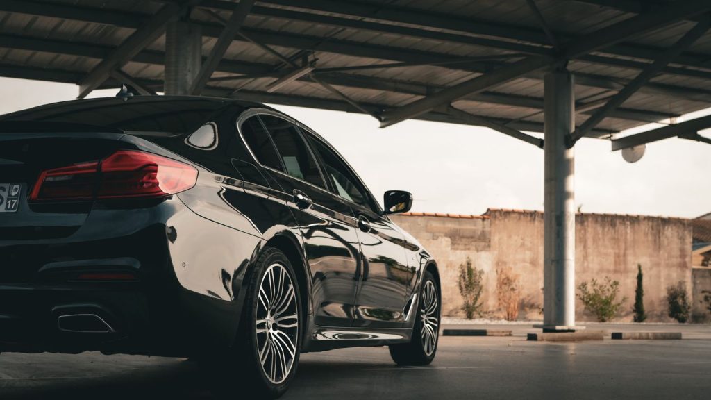 Elegant black luxury sedan parked in a sheltered urban car park, exuding style and sophistication.