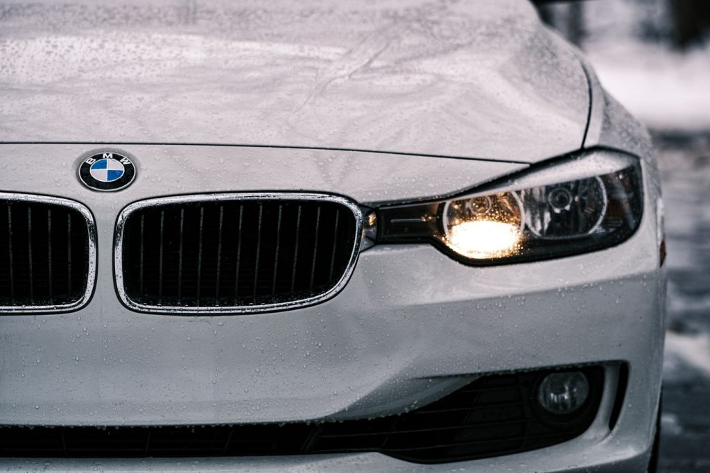 Close-up of a sleek white car front grille and illuminated headlights, showcasing luxury design.