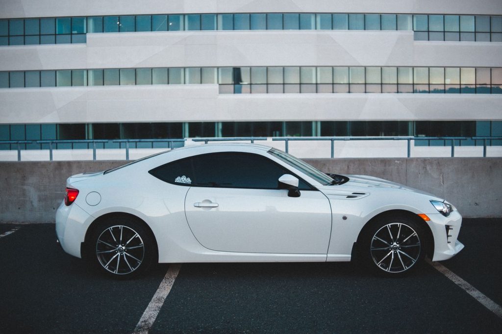 New shiny automobile with silver wheels parked on asphalt with marking lines near building with glass windows